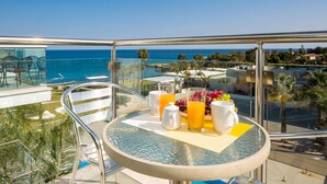 A balcony with a table set for breakfast, overlooking a coastal area with palm trees and a clear sky. - Sharon Sea View - Coralli BeachFront Resort (Paralimni)