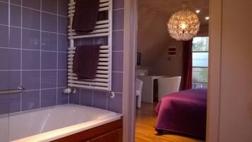 Een badkamer met een bad, een handdoekhouder met twee handdoeken en een douchehoek.