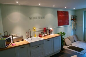 Una cocina con encimera de madera, un lavabo blanco, un tostador y un cartel rojo en la pared.