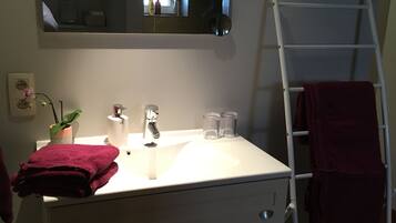 A bathroom with a white vanity, a mirror above the sink, a ladder, and a red towel.