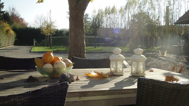 Una terraza de madera con un bol de frutas, dos faroles y sillas.