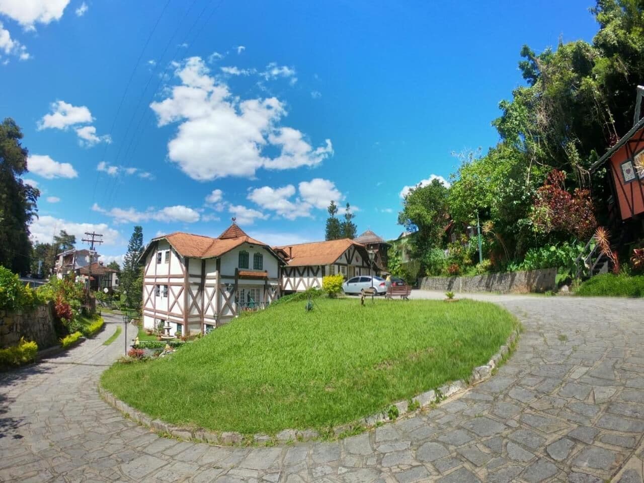 Un pueblo europeo tradicional con calles empedradas de piedra, casas de entramado de madera y un área verde bien cuidada.