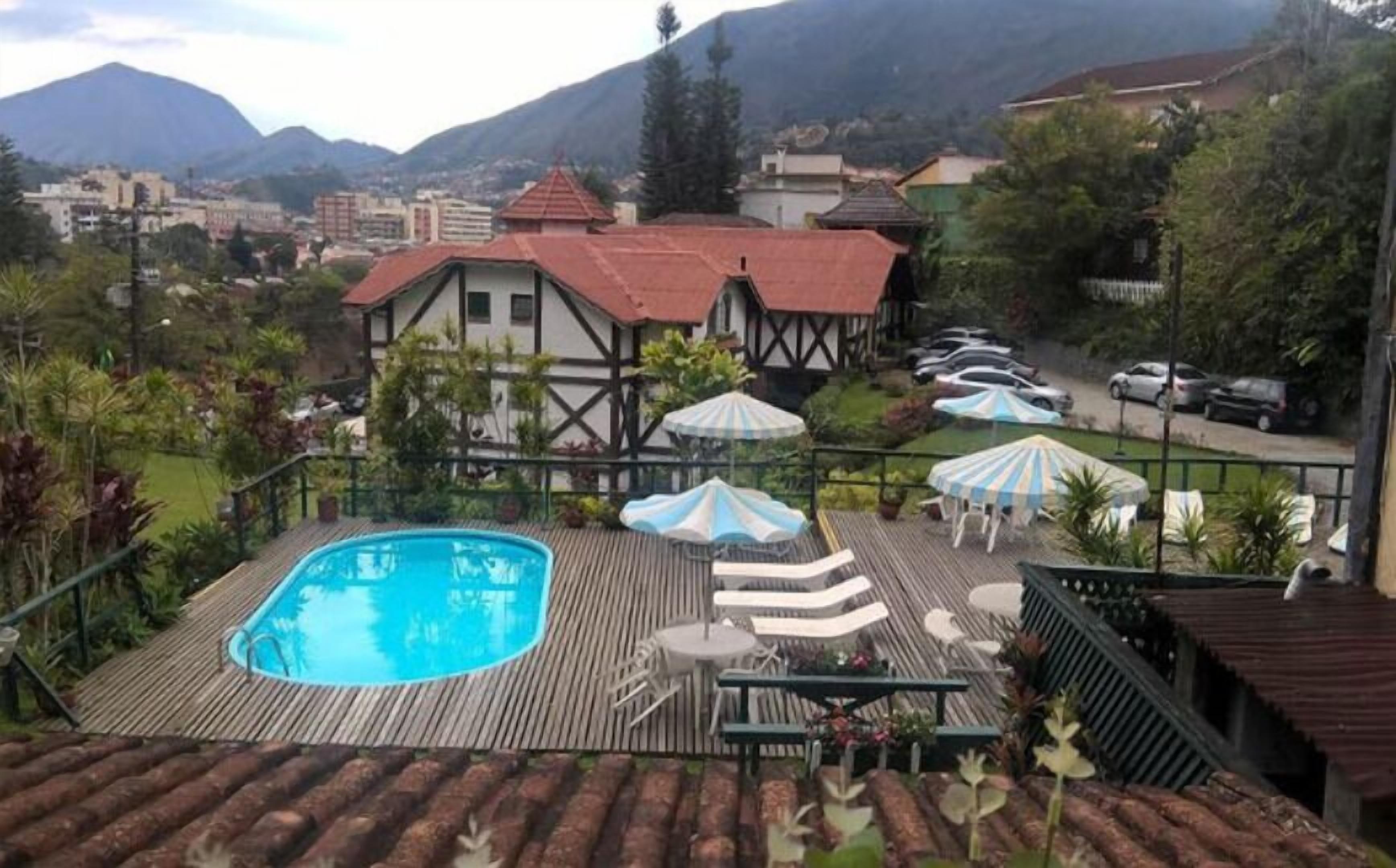 Zona de piscina con muelle de madera, sillas de descanso y sombrillas.