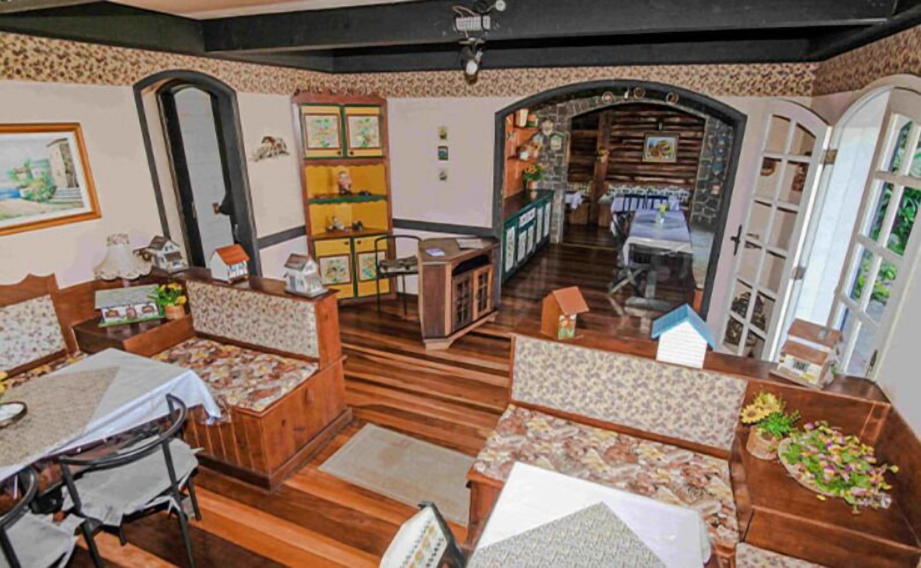 A cozy, well-lit room with wooden flooring, a dining area with a table and chairs, and a kitchen visible through an open doorway.