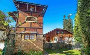 A traditional wooden building with a stone base, a wooden upper section, and a small tower with a crown emblem. - Pousada Chamonix (Teresópolis)