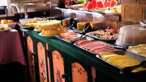 Un bufé con distintos tipos de comida, incluyendo carnes, quesos y postres.