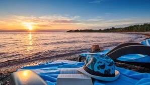 A beach scene with a sunset, a straw hat, a book, and a blue towel. - Superior Mobile Homes Kastanija - Campsite (Novigrad)