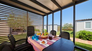 A covered patio with a table set for breakfast, including fruits, bread, and drinks. - Superior Mobile Homes Kastanija - Campsite (Novigrad)