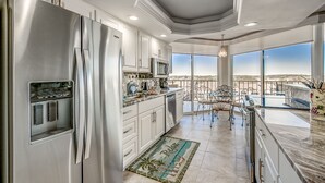 A modern kitchen with stainless steel appliances, a large island, and a view of the city. - Gorgeous condo in Oceanfront Building + Free Attraction Tickets! (Myrtle Beach)