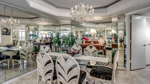 A spacious dining area with a glass table, white wicker chairs, and a chandelier. - Gorgeous condo in Oceanfront Building + Free Attraction Tickets! (Myrtle Beach)