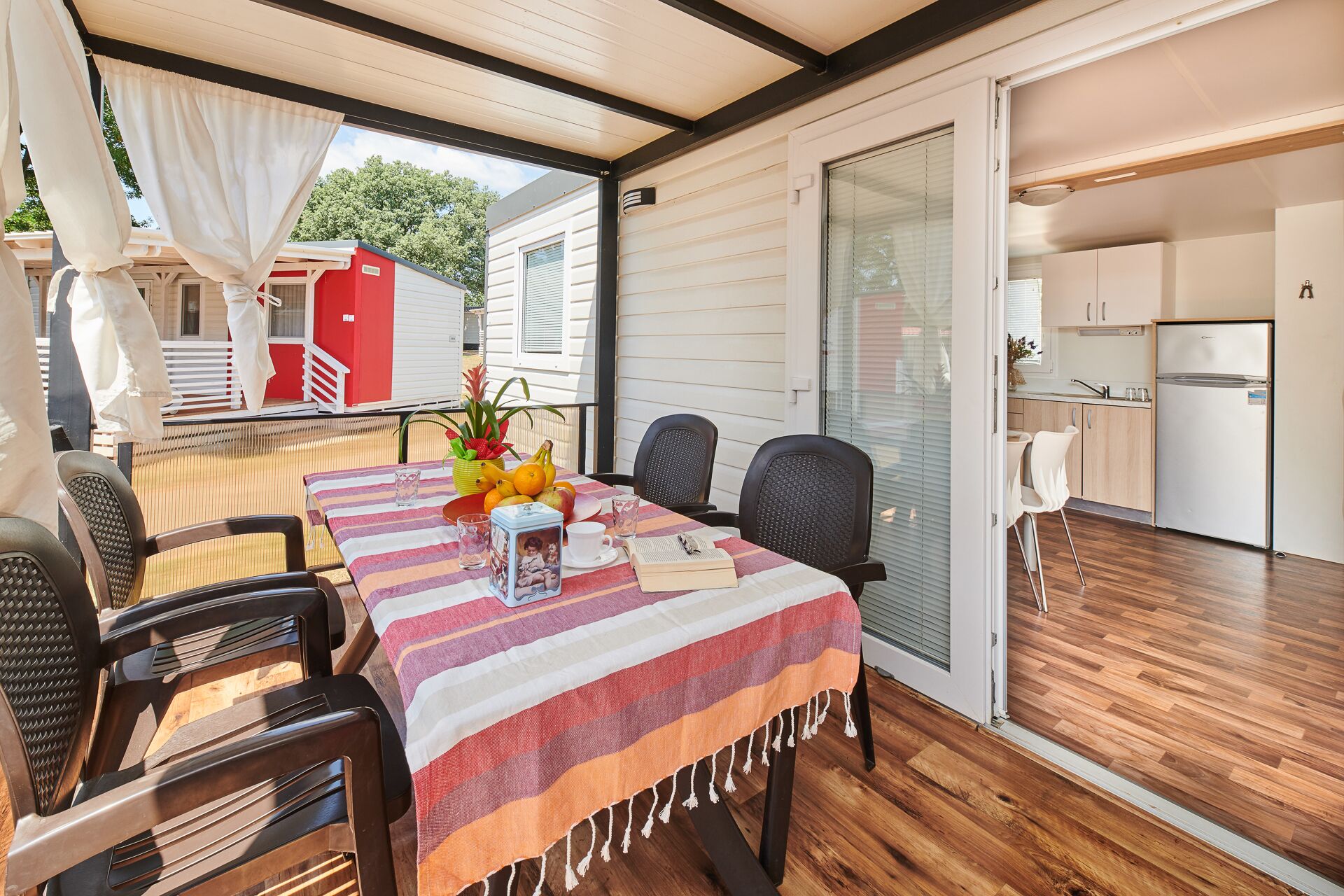 A dining area with a table set for four, chairs, and a view of the kitchen and outside.
