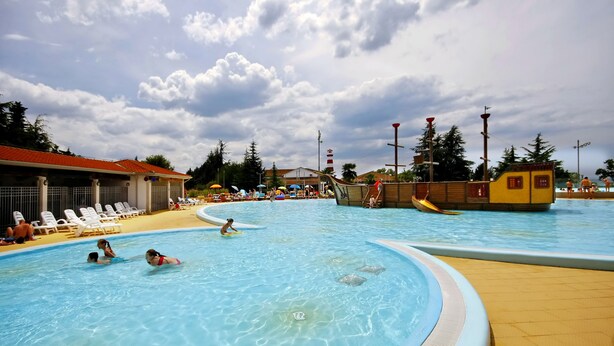 A swimming pool with clear blue water, surrounded by lounge chairs and a wooden deck. - Camping Adria Mobile Homes Park Umag (Brtonigla)