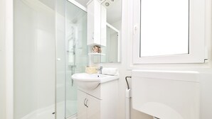 A modern bathroom with a glass shower enclosure, a white sink, and a toilet. - Camping Adria Mobile Homes Park Umag (Brtonigla)