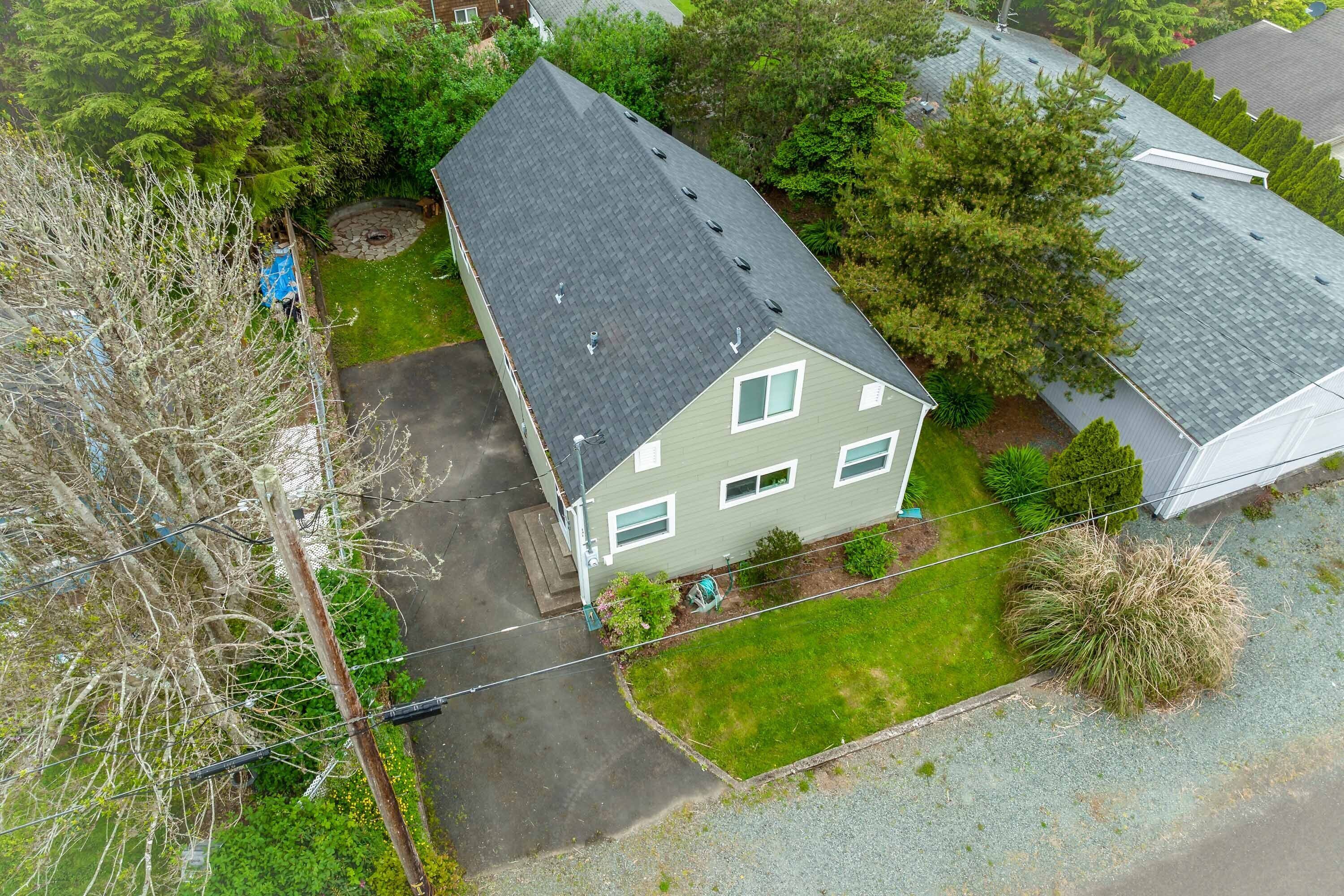 An aerial view of a house with a sloped roof, a front yard, and a driveway.