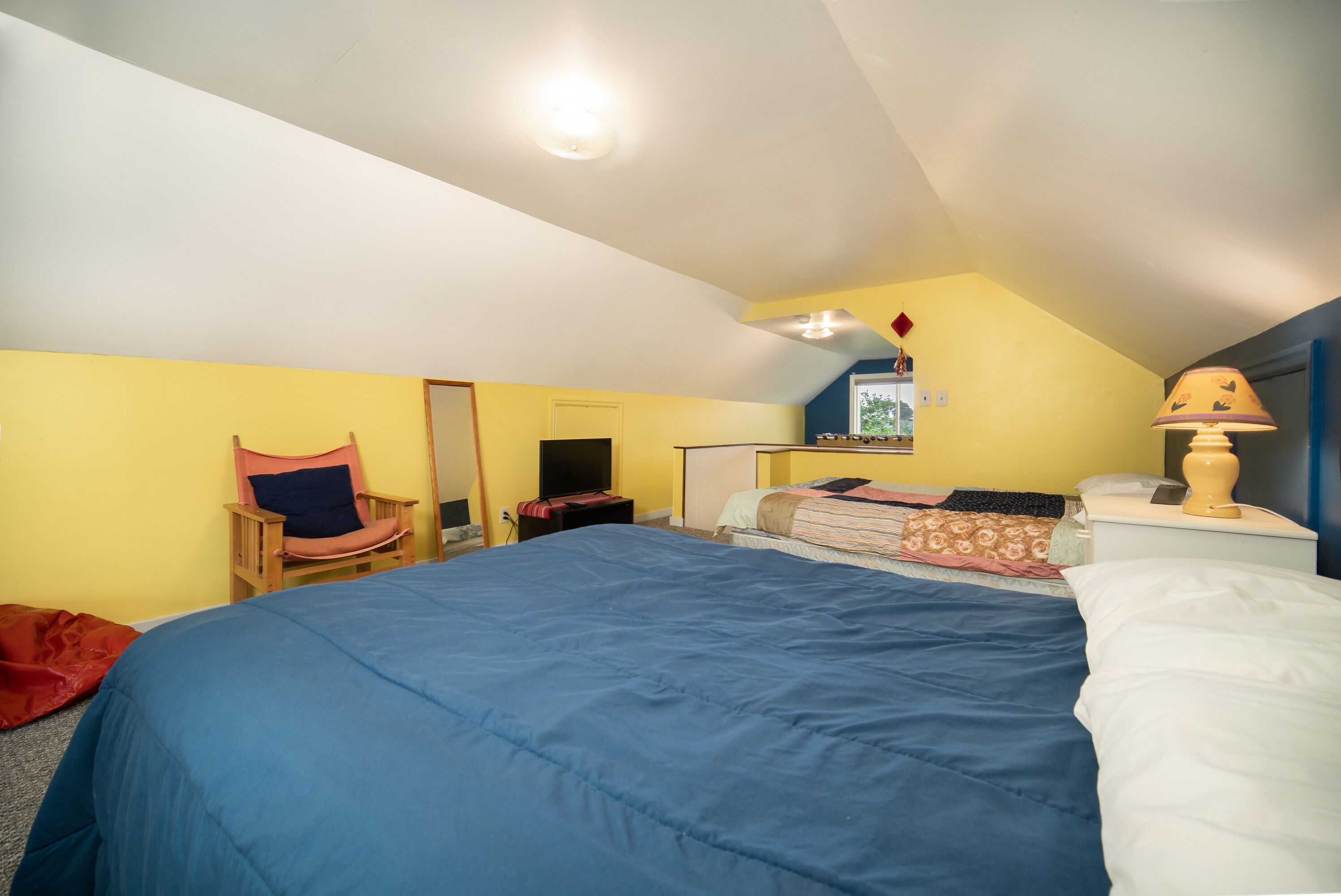 Un dormitorio con una cama grande, una silla, un escritorio y una lámpara.
