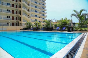 Una piscina al aire libre, sillones reclinables de piscina