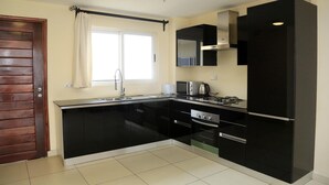 Een moderne keuken met zwarte kastjes, een roestvrijstalen aanrecht, een magnetron, een fornuis en een spoelbak.