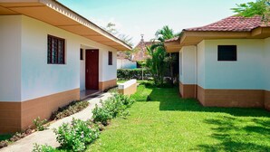Una hilera de casas de dos pisos con un sendero central, rodeada de follaje.