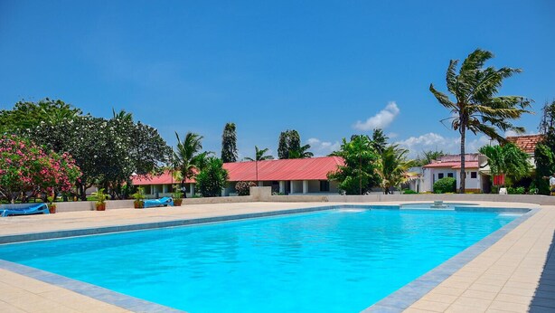 Una piscina rectangular con agua azul cristalina, rodeada por un deck de baldosas.
