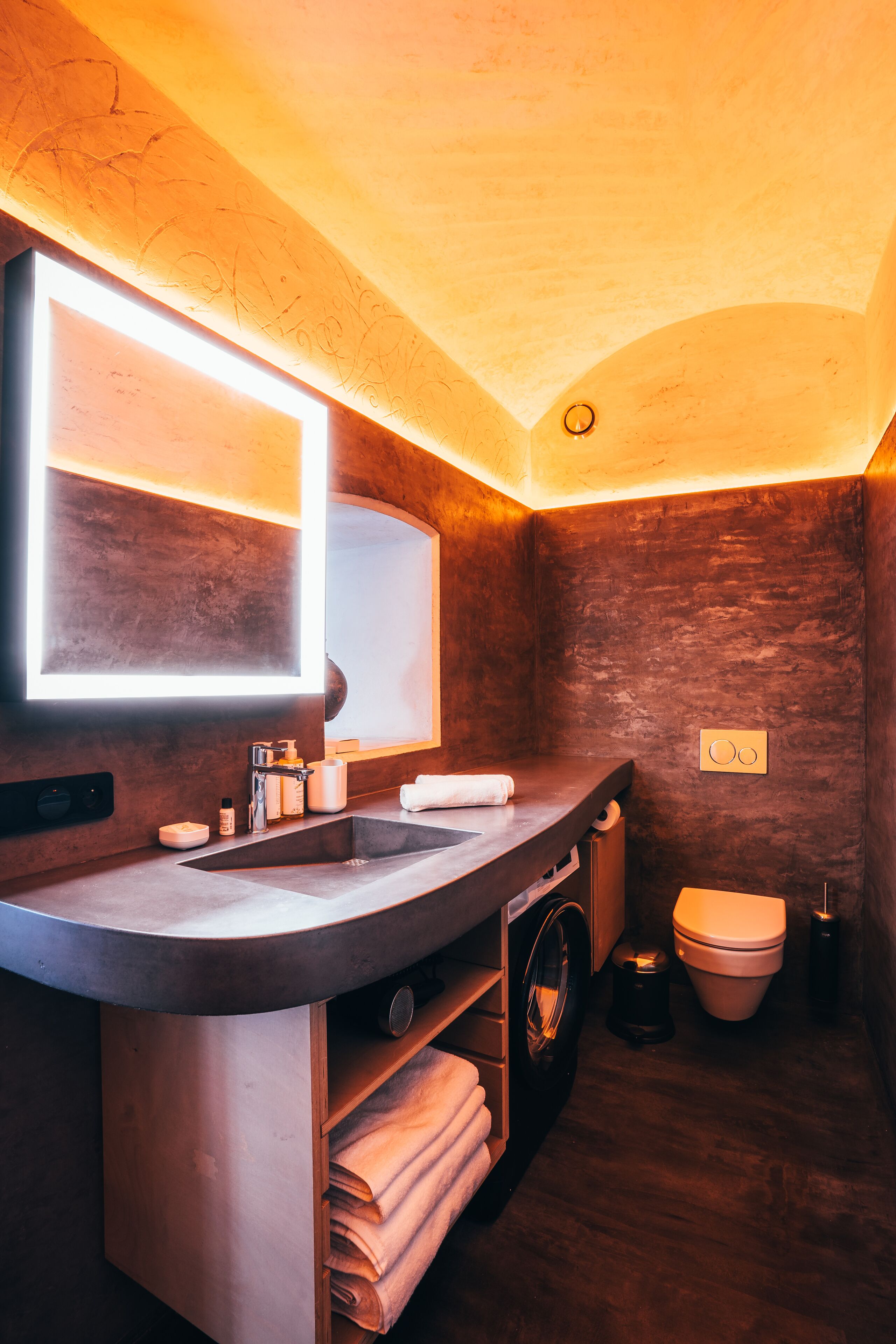 A compact bathroom with a built-in sink, mirror, and toilet.