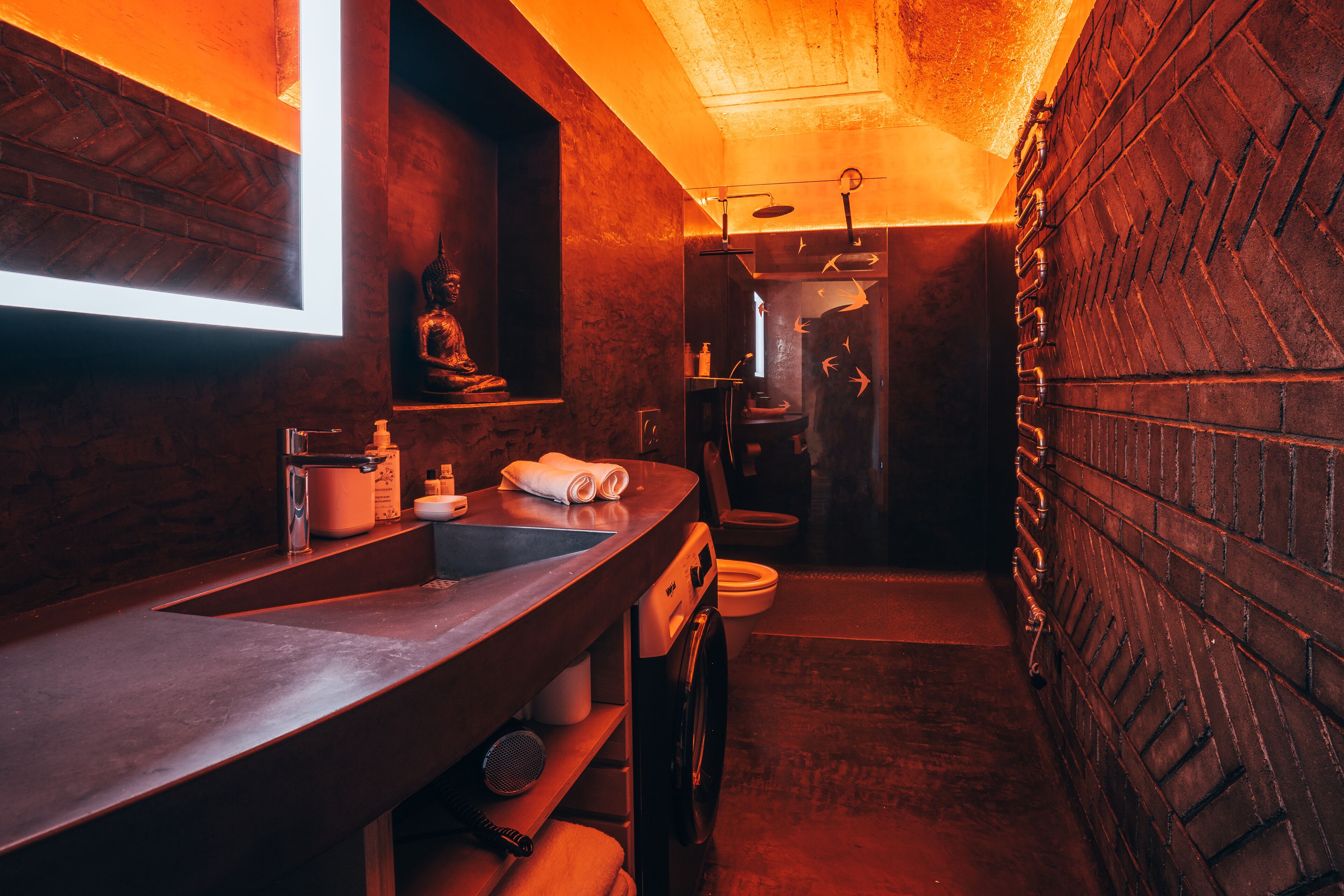 Ein kleines, modernes Badezimmer mit großem Spiegel, Waschbecken und Toilette.
