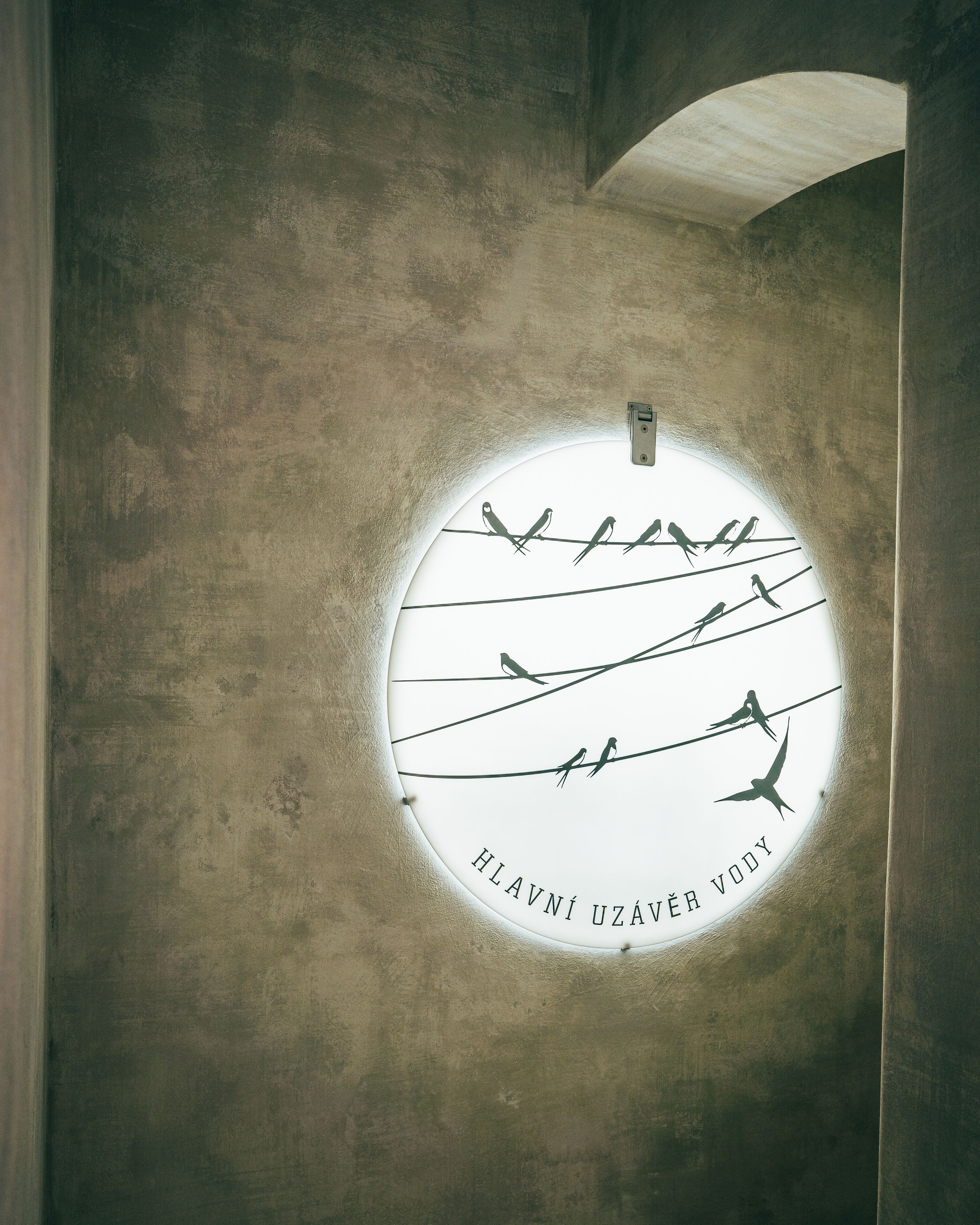 A circular window with silhouettes of birds on wires, and the text "HLAVNÍ UZÁVĚR VODY" is visible.