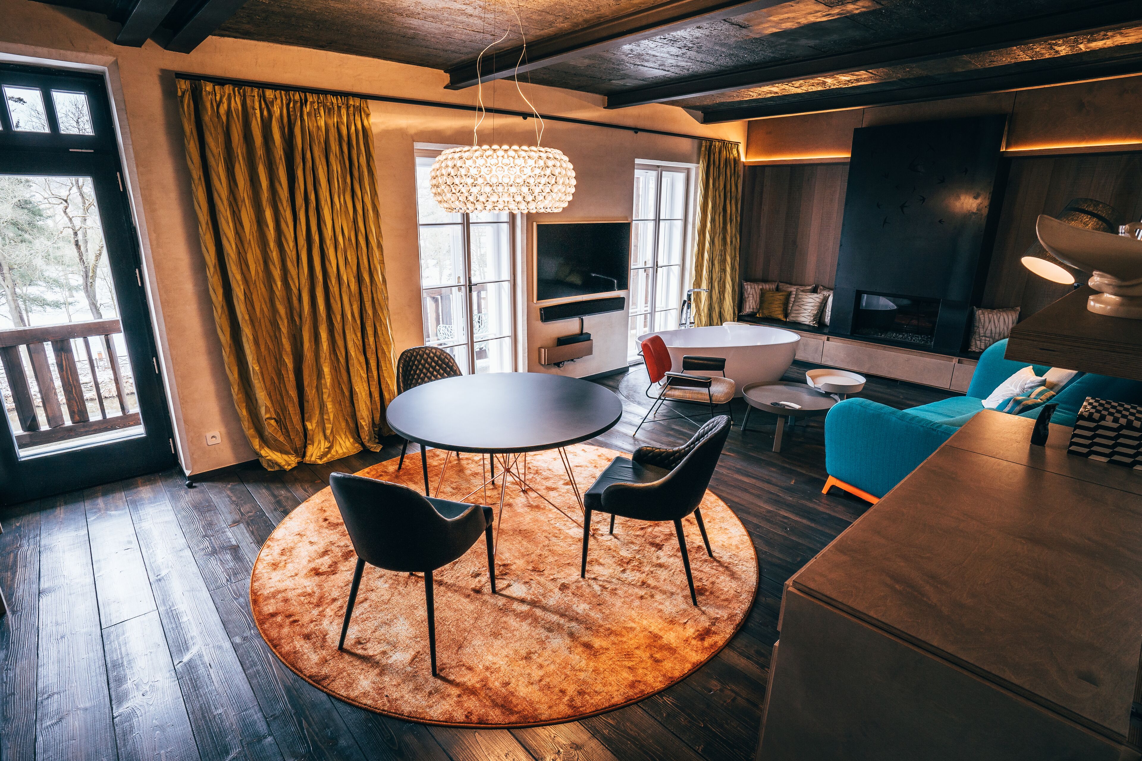 A modern living room with a round table, two chairs, a sofa, and a TV.