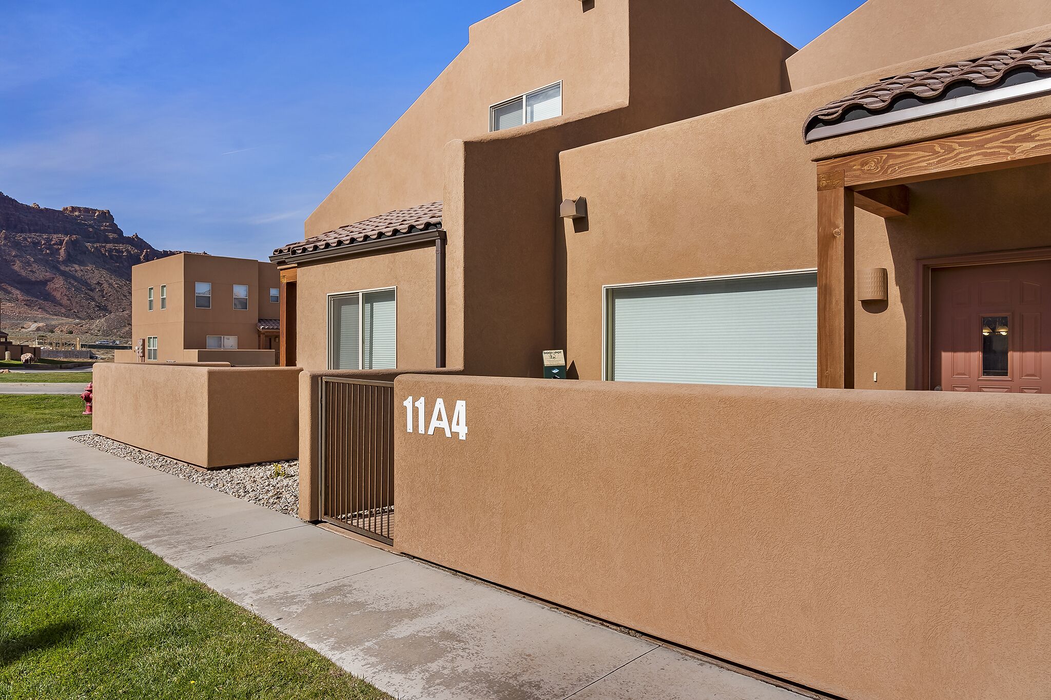 A modern building with a flat roof, beige exterior walls, and a numbered address sign.