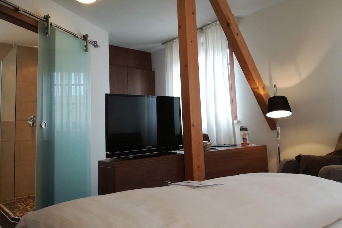 Hotelkamer met een bed, een flatscreen-tv, een houten bureau, een lamp en een schuifdeur.