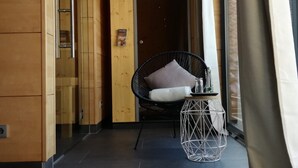 A modern interior with a wooden wall, a black chair with a cushion, a glass cabinet, and a cowhide rug.