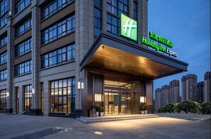 Um hotel Holiday Inn Express com fachada moderna, janelas amplas e entrada bem iluminada.