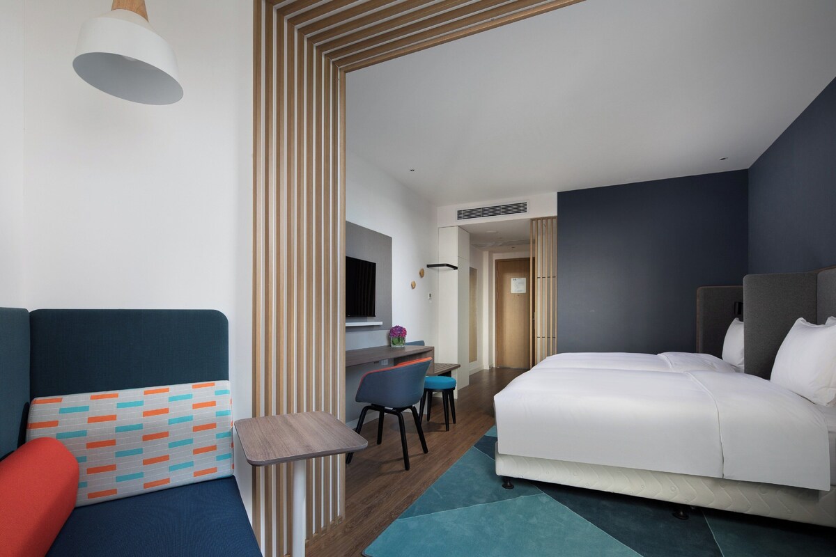 Una habitación de hotel moderna con una cama, un escritorio y una zona de estar.