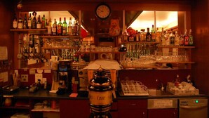 A bar with shelves of liquor bottles, a clock, and a teddy bear.
