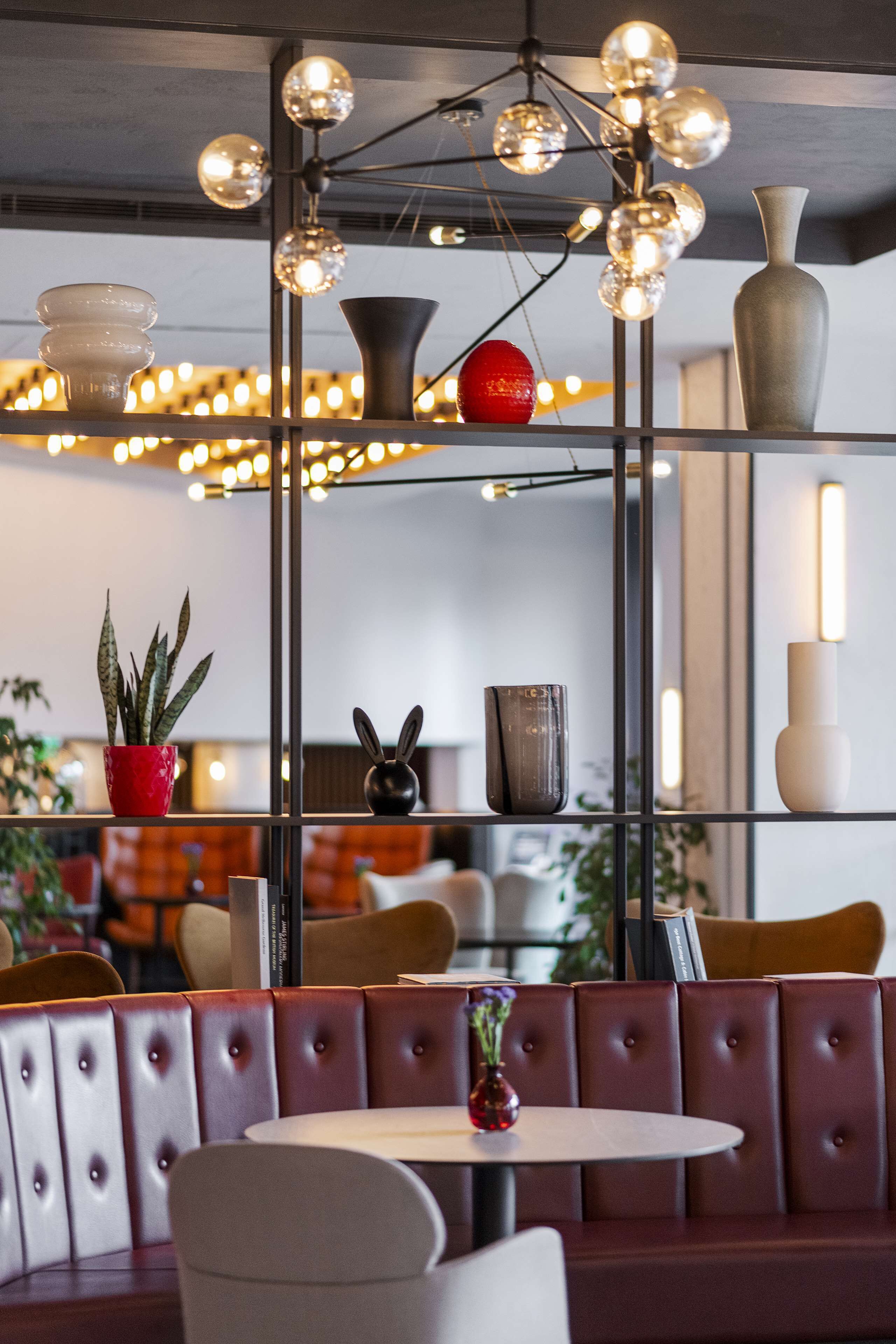 A restaurant interior with a booth seating area, a round table, and a decorative light fixture above.