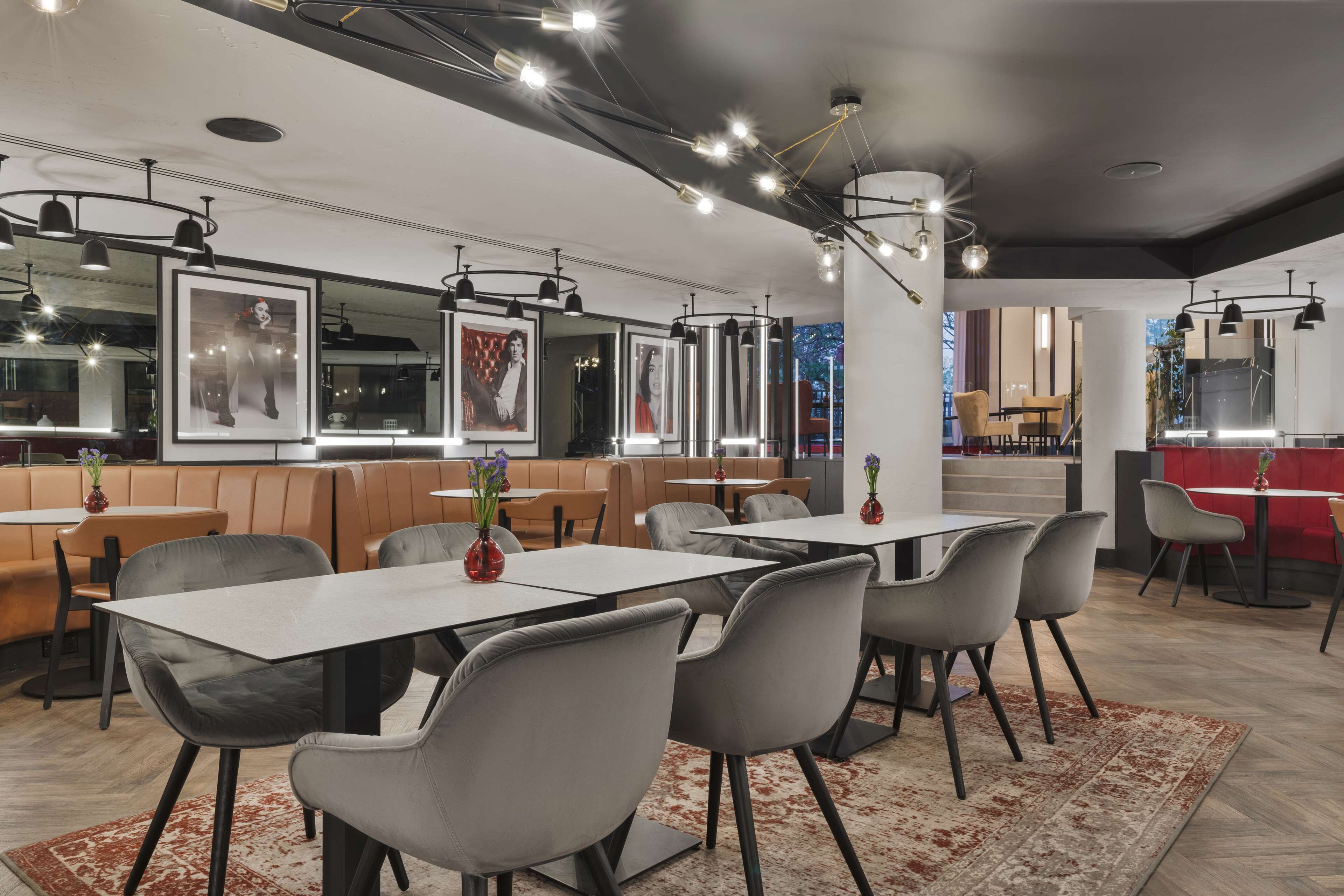 A modern restaurant with booths and tables, pendant lighting, and framed artwork on the walls.
