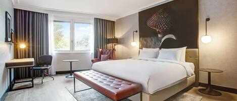Una habitación de hotel moderna con una cama grande, un escritorio, una silla y un banco.