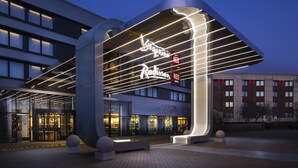 A hotel entrance with a curved awning, glass doors, and a sign indicating a 'Red Bed' room.