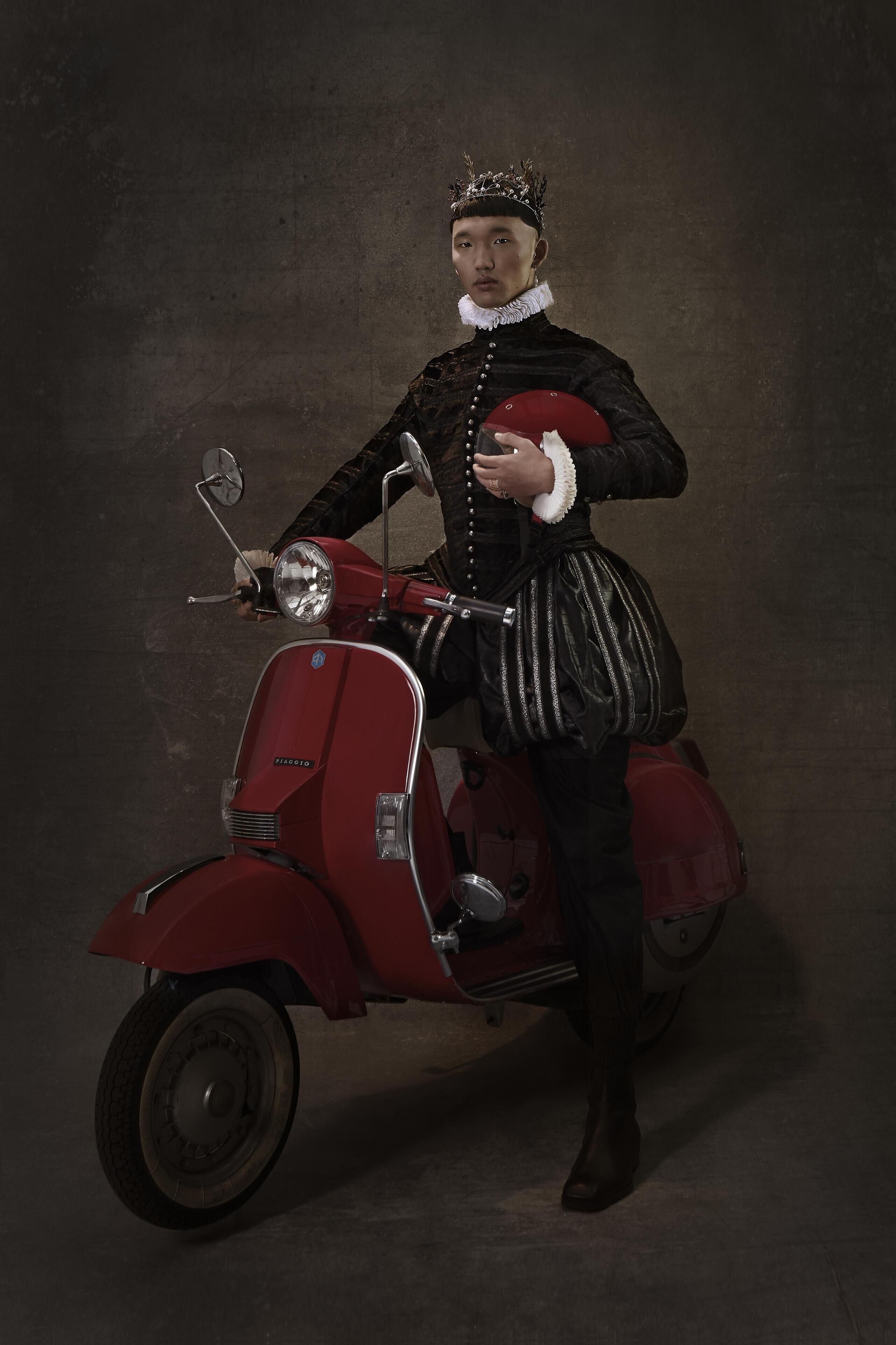 A person in historical costume sitting on a red scooter.