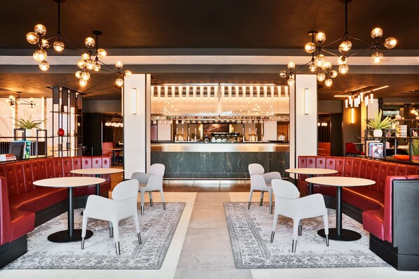 A modern bar area with red booths, white tables, and hanging spherical light fixtures.