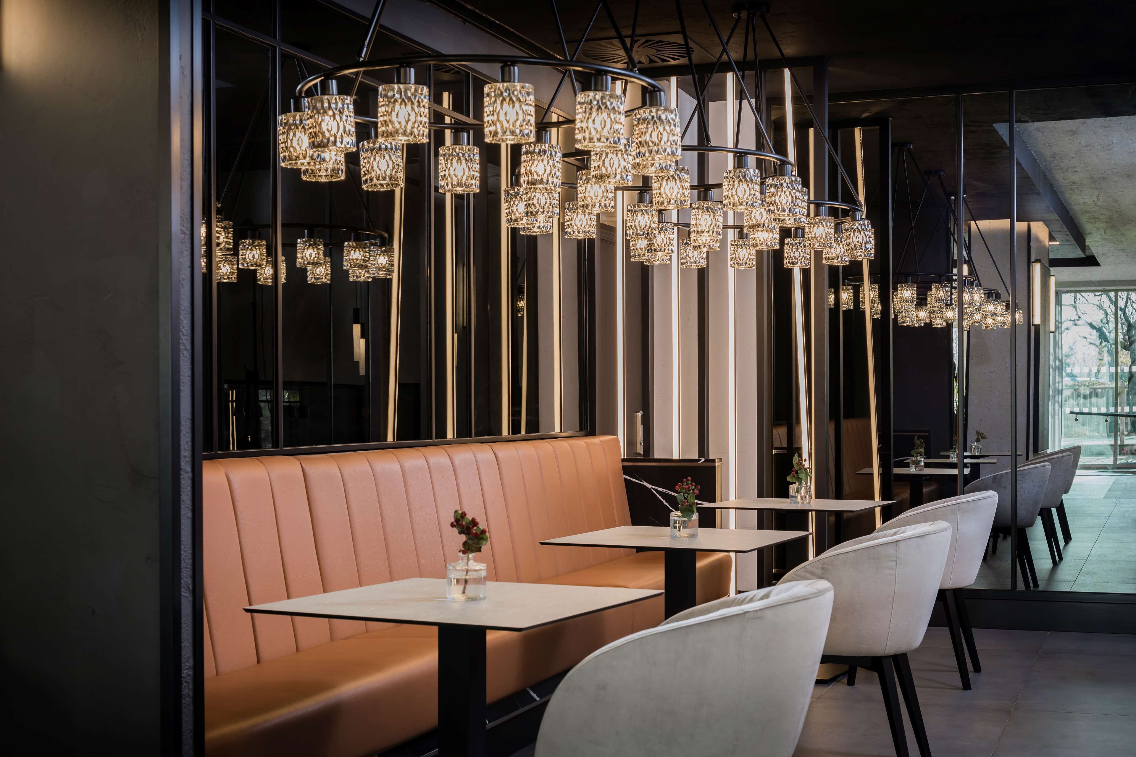 A modern dining area with a booth seating arrangement, pendant lighting, and a view of the outdoors.