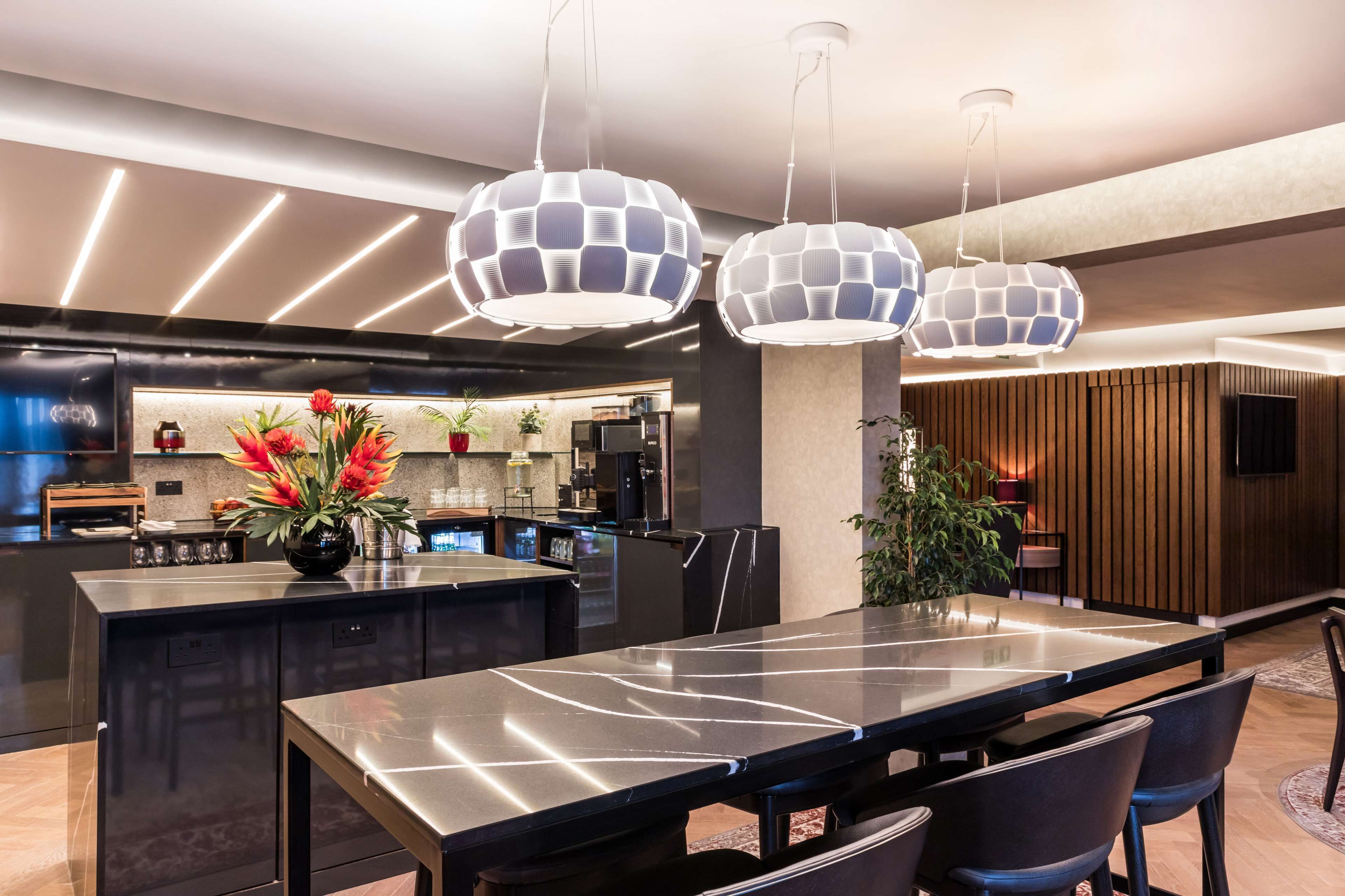 A modern kitchen with a central island, pendant lighting, and a dining area with a long table and chairs.