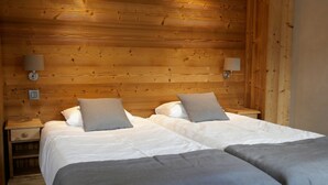 Une chambre double avec deux lits, chacun étant équipé d’un oreiller et d’une table de chevet.