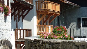 Un chalet traditionnel doté de balcons en bois, de murs en pierre et de jardinières fleuries.