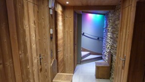 Un couloir en bois avec un mur en pierre et un escalier menant à une pièce.