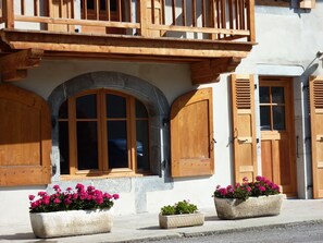 A building with a balcony, wooden shutters, and flower planters. - Independent apartment in a beautifully renovated old house in the village center (Samoens)