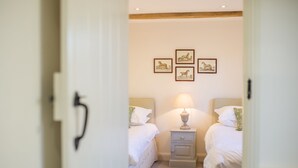 A bedroom with two beds, a nightstand with a lamp, and three framed pictures on the wall. - Broomhill Cottage  - sleeps 4 guests  in 2 bedrooms (Midhurst)