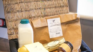 A wicker basket with a label, a milk carton, a brown paper bag, and a yellow item. - Broomhill Cottage  - sleeps 4 guests  in 2 bedrooms (Midhurst)