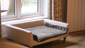 A room with a window, a cushioned bench, a door, and a curtain. - Broomhill Cottage  - sleeps 4 guests  in 2 bedrooms (Midhurst)