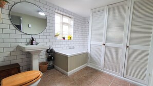 A bathroom with a sink, mirror, toilet, and a window with potted plants. - Beautiful, Quiet, Countryside Cottage in the foothills of the Cotswolds (Witney)
