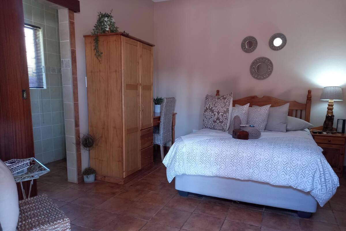Une chambre à coucher avec un lit, une armoire en bois et une petite table sur laquelle est posée une plante.